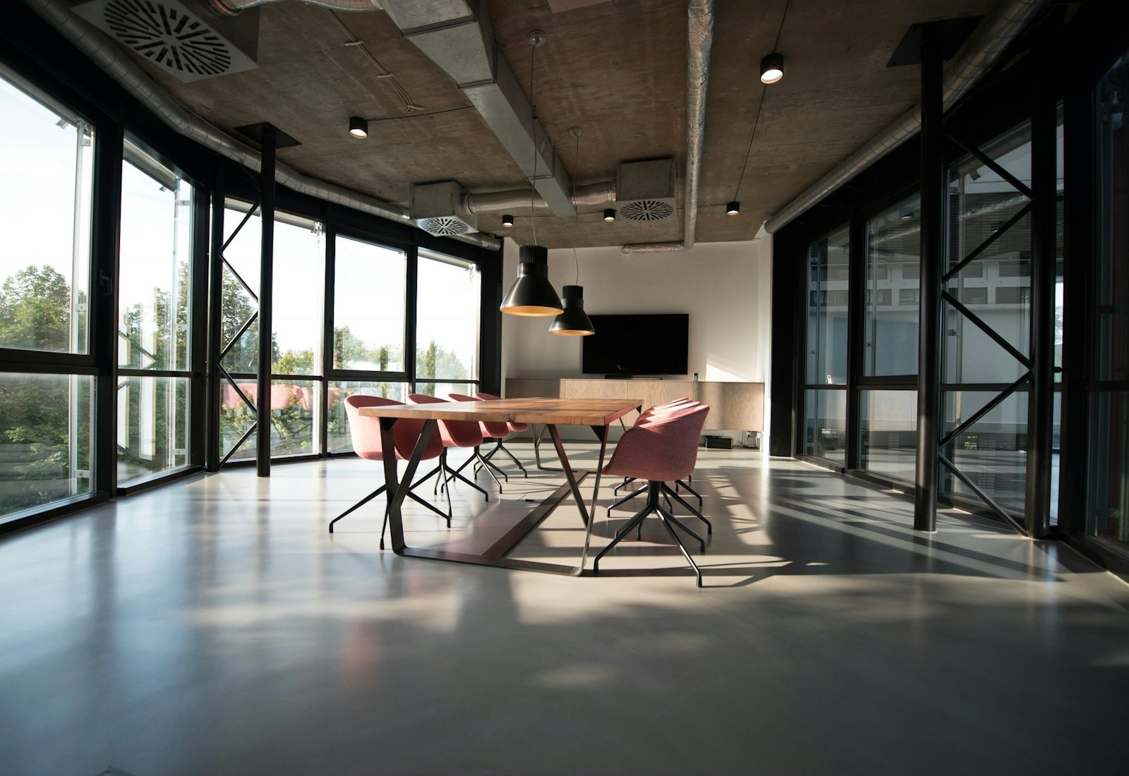 Daylit office atrium with a long work table and concrete columns