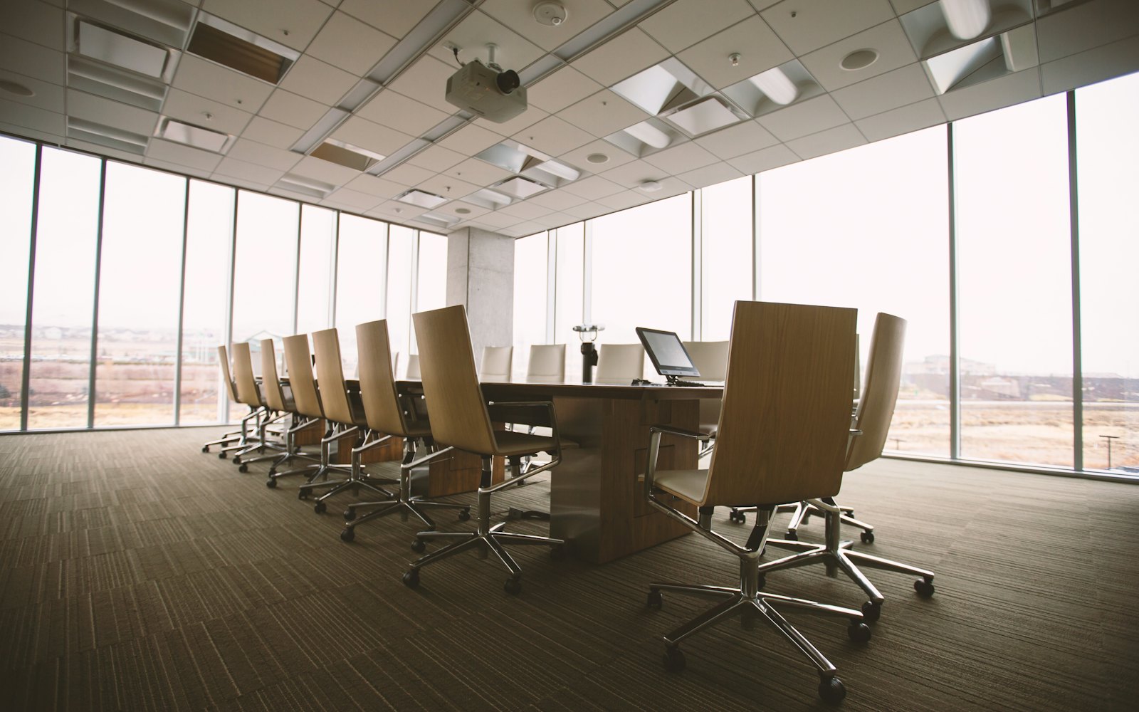 Long empty boardroom with daylight, a pale table, and chairs set for a working session
