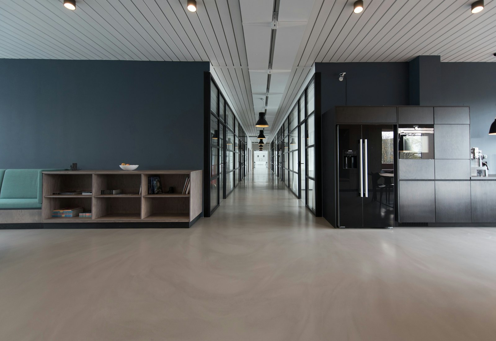 Bright office corridor with glass rooms and a pale floor