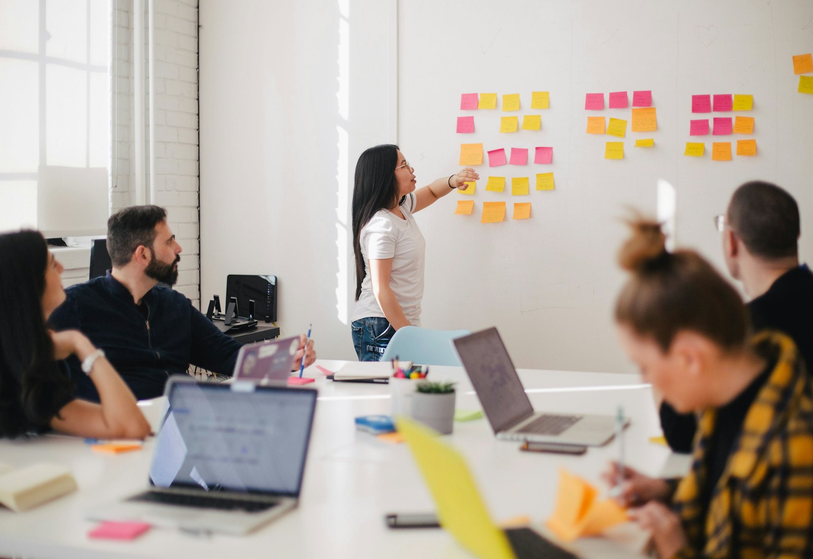 Small team standing around a table reviewing printed notes in a bright room